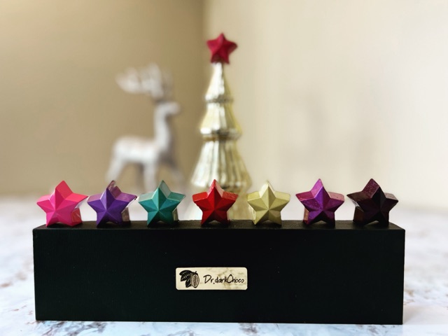 Seven colorful faceted star chocolates arranged above a black Dr.darkChoco gift box